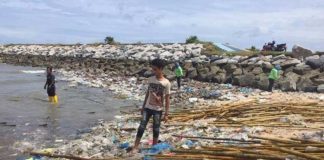 Sattahip bay, thai man stood on rubbish floating in sea