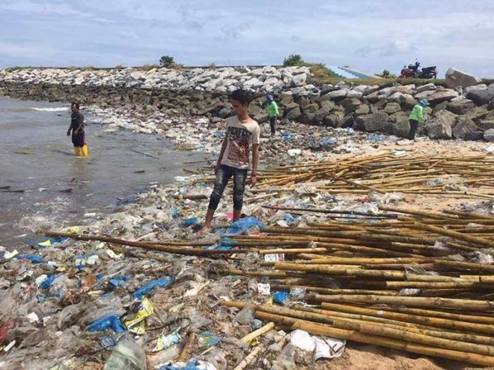 Sattahip bay, thai man stood on rubbish floating in sea